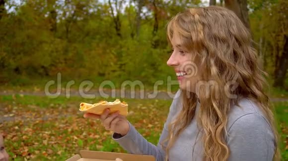 一位母亲给她的披萨喂了一个小男孩秋天公园的家庭野餐视频的预览图
