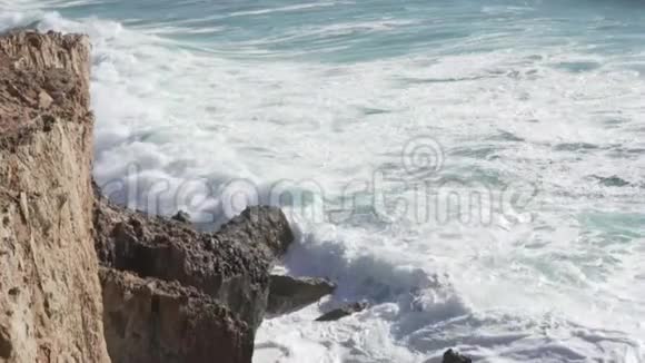 波浪在岩石上跳动从海洋上方的悬崖俯瞰视频的预览图