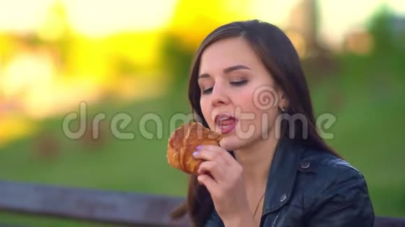 公园里的女孩吃着面包电话铃响了她接电话视频的预览图