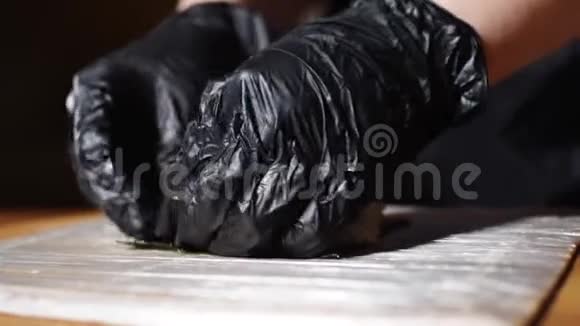 寿司大师的特写他的手戴着黑色手套做美味的寿司用竹垫卷框架传统视频的预览图