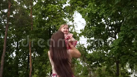 宝贝和妈妈一起在空中飞翔孩子微笑着和父母在公园里玩耍和散步慢动作视频的预览图