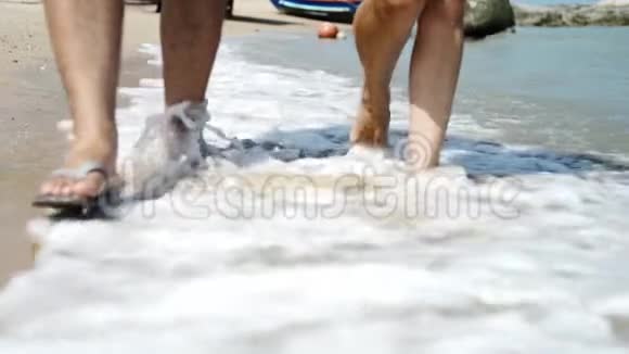 一对情侣在海滩上走得很近把脚和腿关起来浪漫的女人和男人暑假视频的预览图