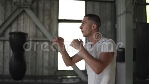 运动短裤T恤拳击拳打脚踢的强壮青年在健身房锻炼时的侧视视频的预览图