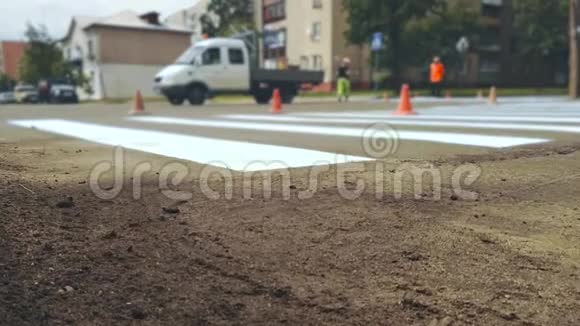 工人在城市街道沥青十字路口用油漆水平道路标记斑马线视频的预览图