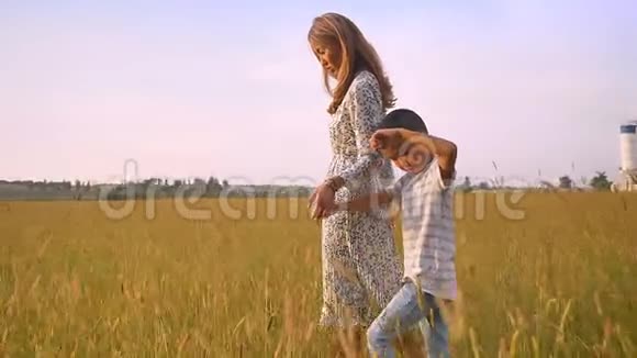 亚洲的儿子和他美丽的母亲温柔地牵着他们的手走在黄野上视频的预览图