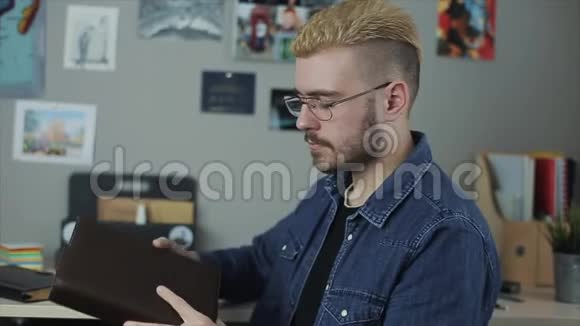 英俊时尚的男人快乐的脸拿着书竖起大拇指有黄头发的嬉皮士为一本书做广告家庭视频的预览图