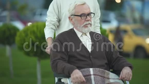 残疾老年男性坐轮椅抚摸年轻女性的手家庭视频的预览图