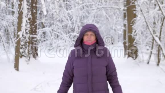 老妇人向前走在冬天的森林里微笑视频的预览图