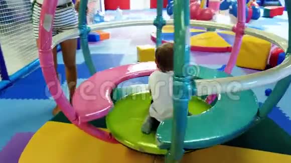 在商场的游乐园里幼儿男孩骑着五颜六色的旋转木马视频的预览图