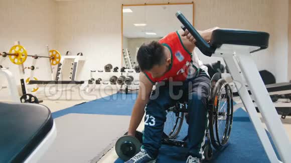 坐轮椅的英俊残疾人在有重量的健身房训练视频的预览图