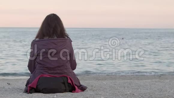 4K女人坐在沙滩上享受着平静的大海转过头来从后面射门视频的预览图