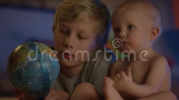 可爱的孩子只是坐在坏的地方玩地球仪他的兄弟做公司视频的预览图