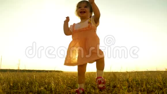 女孩迈出第一步微笑着面对田野里的夕阳慢动作视频的预览图