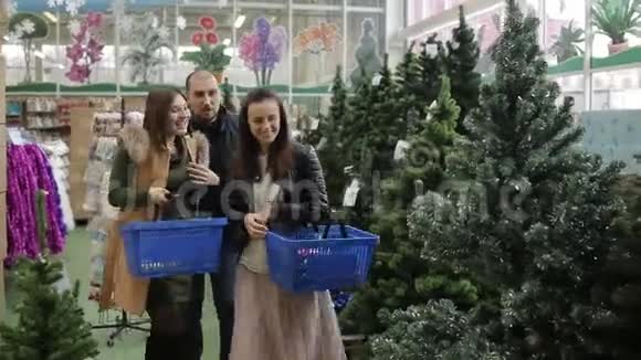 一群朋友在超市的圣诞义卖活动中在人造圣诞树中选择圣诞节视频的预览图