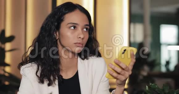 疲惫的商务女性在咖啡馆里使用智能手机坐在现代同事间喝酒的女孩视频的预览图