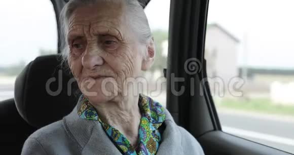一位长着深深皱纹和白发的老妇人坐在汽车的后座上视频的预览图