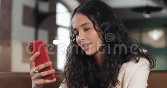 商务女性在智能手机上使用应用程序在咖啡馆微笑在手机上发短信漂亮的休闲女性职业视频的预览图