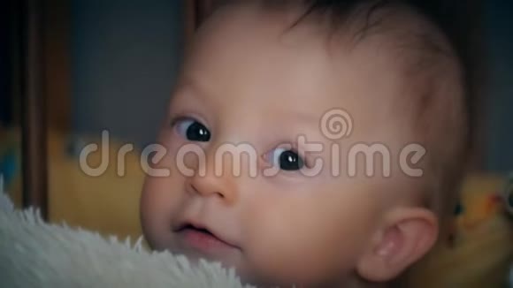 闭上宝宝的脸同时微笑和笑一个可爱的小宝宝正在看镜头视频的预览图