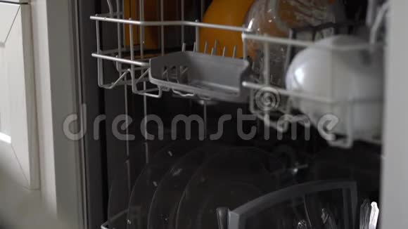 一个女人打开洗碗机在里面放了一个脏盘子视频的预览图