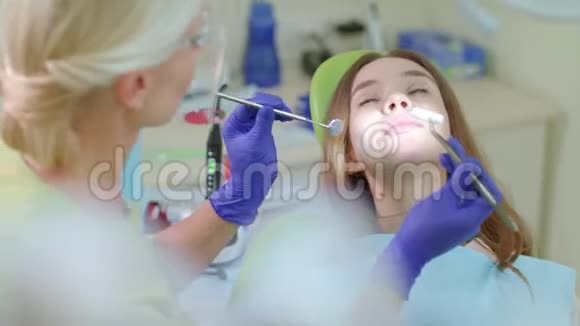 牙疼的病人坐在牙医椅上为女孩工作的牙医视频的预览图