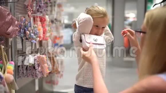 快乐的一家人在购物在商场里的家人妈妈和小女儿在服装店买女孩子的衣服视频的预览图