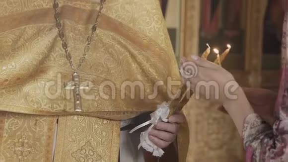 东正教洗礼仪式牧师用字体点燃蜡烛的特写视频的预览图