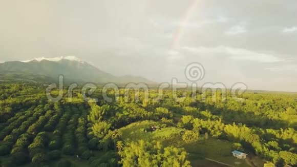 青山和五彩缤纷的彩虹越过农业田和水果种植村空中景观水果视频的预览图