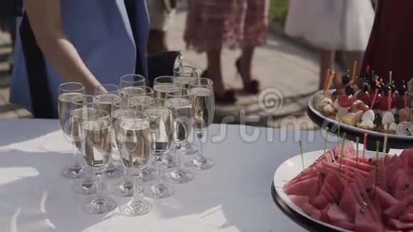 提供带香槟水果和罐头的自助餐女人从桌子上拿了一杯香槟和一份零食视频的预览图