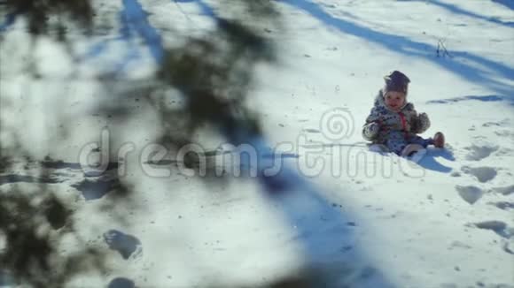 4K家庭冬季运动会这孩子正坐在公园的雪地上视频的预览图