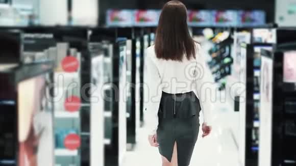 从侧面看女人在货架之间的化妆品店里慢动作视频的预览图
