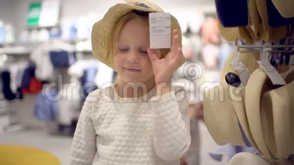 小女孩在超市里挑选衣服快乐的一家人在购物在商场里的家人挑选婴儿帽视频的预览图