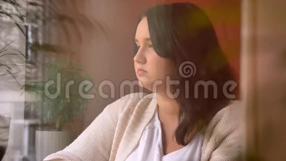 大白种人中性女性在窗边喝咖啡的肖像视频的预览图