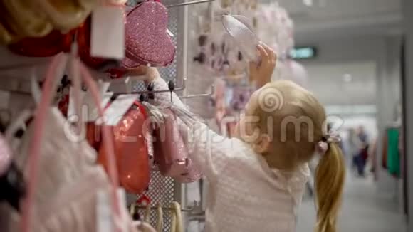 小女孩在超市里挑选衣服快乐的一家人在购物在商场里的家人选择一个婴儿手袋视频的预览图