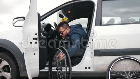 一个坐在车里的残疾人把他的轮椅放在一辆车里捡起来他准备好乘车了视频的预览图