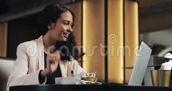 有魅力的商务女性在舒适的咖啡馆里午休时吃沙拉在笔记本电脑上玩电视游戏视频的预览图