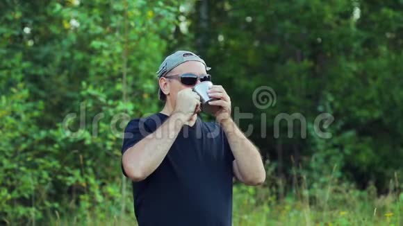森林边缘的一个人从杯子里喝茶欣赏大自然视频的预览图