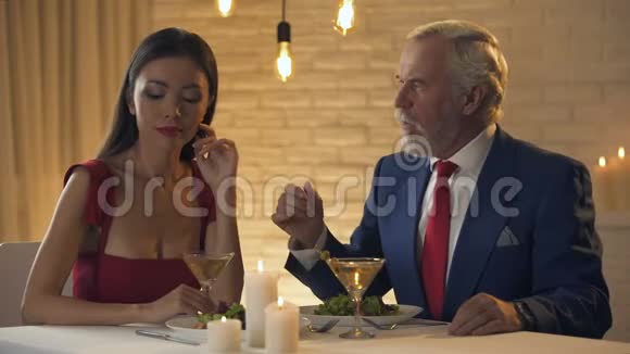 老人亲吻年轻被冒犯的妻子的手在餐馆里浪漫的约会视频的预览图