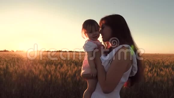 妈妈抱着小女儿在美丽的晚霞中穿过麦田视频的预览图