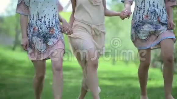 美丽的新娘和伴娘穿着连衣裙光着脚在公园的户外互相跑步新娘婚礼日视频的预览图