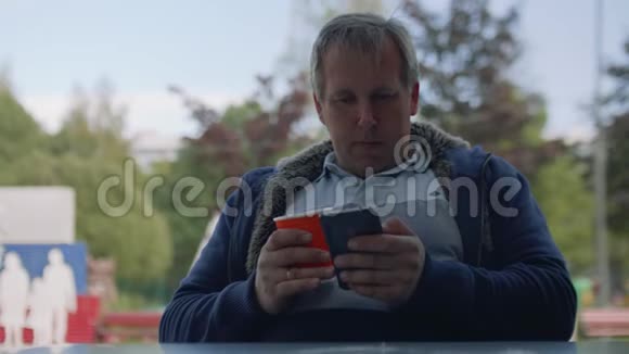 一个穿着t恤手里拿着纸杯咖啡的人在智能手机上上网视频的预览图