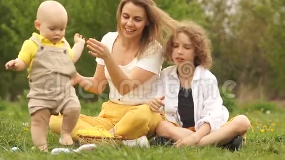 复活节那天可爱的孩子们和妈妈在春天的公园里寻找彩蛋传统复活节视频的预览图