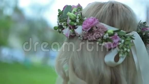 美丽的金发女孩头上戴着花圈慢慢地走着新娘婚礼日视频的预览图