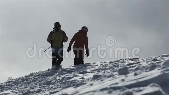 滑雪板带着滑雪板在雪山上走到山顶滑雪者在雪山峰上站起来骑马视频的预览图