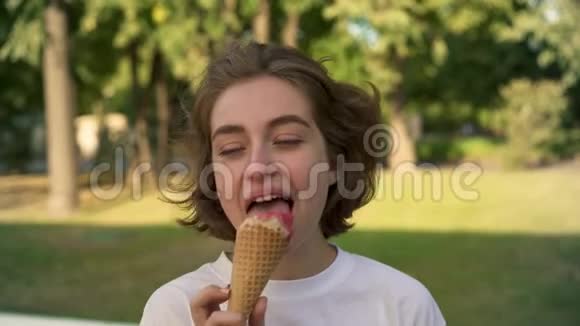 年轻的金发少女在夏天公园享受冰淇淋视频的预览图