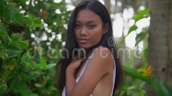 美丽的亚洲年轻女子穿着白色上衣在外面性感的女孩摆在狂野的小路上视频的预览图
