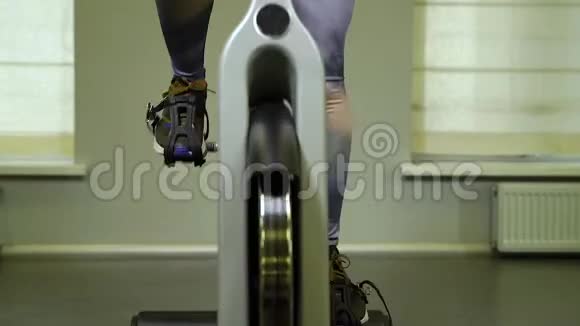 在健身房骑自行车来适应年轻女人强壮的女运动员在健康俱乐部做循环有氧运动视频的预览图
