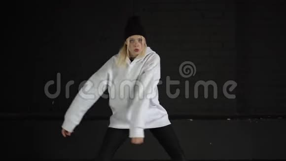 慢动作穿着白色衣服在黑墙的房间里跳嘻哈舞的女孩视频的预览图