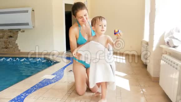 游泳后年轻母亲用大白巾擦拭孩子的4k视频视频的预览图