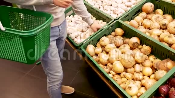 年轻人手里拿着超市里的蔬菜放到蔬菜部的篮子里视频的预览图