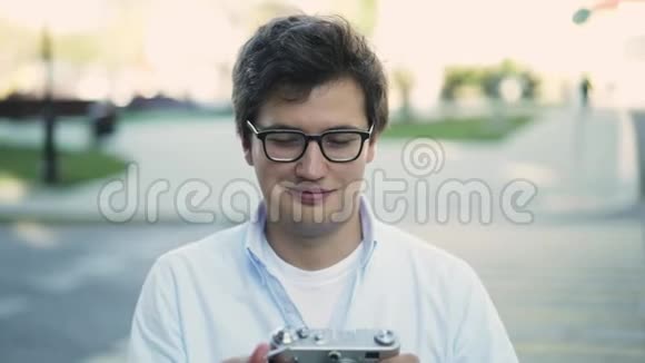 戴眼镜的帅哥用老式相机拍照微笑视频的预览图